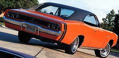 an orange muscle car parked on the street