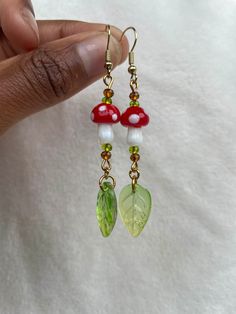 a pair of earrings with mushrooms and leaves hanging from them