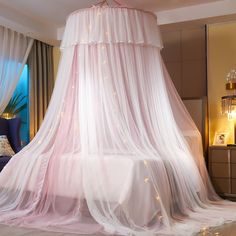 a canopy bed with white sheer curtains and lights on the ceiling, in a bedroom