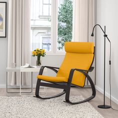 a yellow rocking chair in front of a window with a white rug on the floor