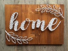 the word home is made out of wire on a wooden board with leaves and branches