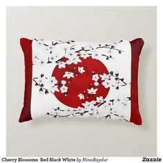 a red and white pillow with cherry blossoms on the front, along with a black and white background