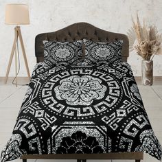 a bed with a black and white comforter on top of it next to a lamp