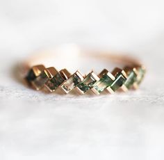 a close up of a gold ring with green stones