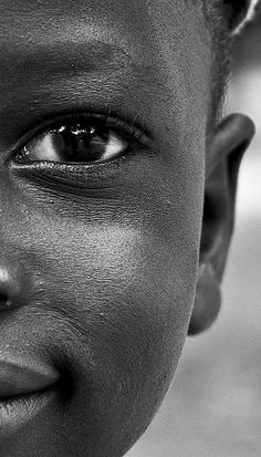 a black and white photo of a young boy smiling at the camera with his eyes wide open