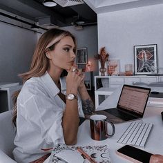 a woman sitting at a desk with a laptop and coffee cup in front of her