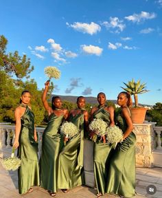 four beautiful women in green dresses holding flowers