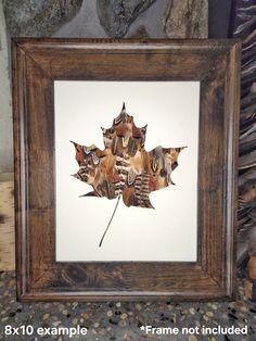 an image of a leaf made out of leaves in a wooden frame on a table