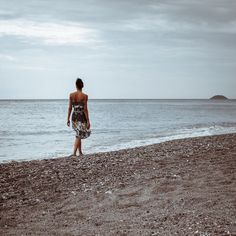 a woman standing on top of a beach next to the ocean