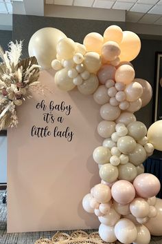 a baby it's a little lady balloon arch with white and gold balloons on top