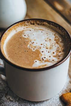 there is a cup of hot chocolate on the table next to some sugar and a cookie