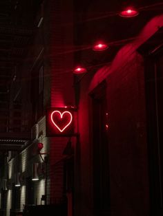 a red neon heart sign hanging from the side of a building