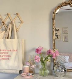 pink flowers in vases are sitting on a dresser next to a mirror and purse