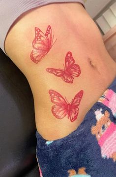 a woman's stomach with three red butterflies on her side and the lower part of her abdomen