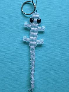 a cross shaped keychain is hanging on a blue surface with two keys attached to it