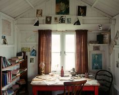 a table and chairs in a room with pictures hanging on the wall above it's windows