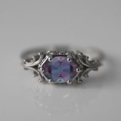 a ring with a purple stone in the center and filigrees around it