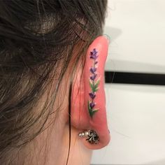 a woman with tattoos on her ear and behind the ear is an image of flowers