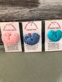 three crochet hearts are on display for sale