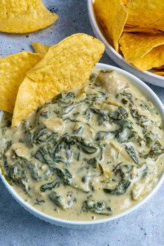 spinach dip with tortilla chips on the side and in a white bowl