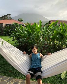 a young boy is sitting in a hammock