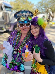 two women dressed in mardi gras costumes posing for the camera with one holding a bottle