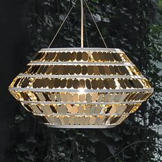 a light fixture hanging from a ceiling in front of trees