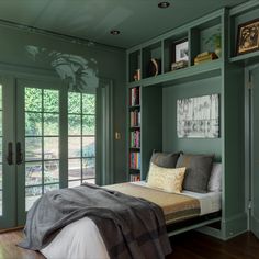 a bedroom with green walls and built - in bookshelves, bedding, and pillows