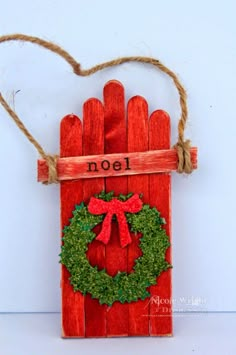 a wooden sign with a wreath on it and the word noel spelled in red paint