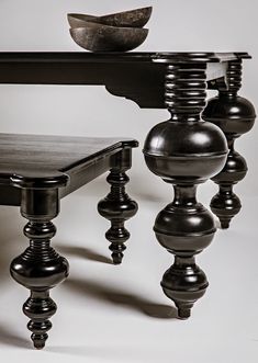 a black table with four wooden balls on it and a bowl sitting on top of the table