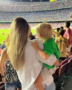 a woman holding a child in her arms at a baseball game