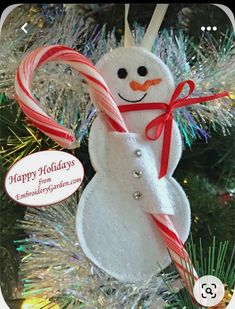 a snowman ornament hanging from a christmas tree with candy canes in it