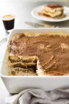 a pan filled with chocolate cake next to two cups of coffee on a table top