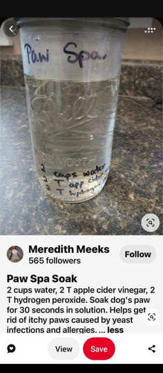 a glass jar filled with water sitting on top of a counter next to a phone