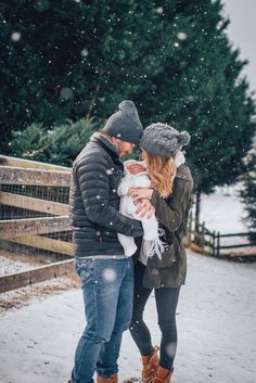 a man and woman holding a baby in the snow