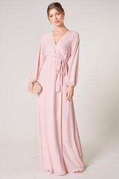 Warm and inviting, the Wholehearted Maxi Dress is a perfect combination of modest and sultry. Long balloon sleeves frame a surplice neckline separated by a tie at the waist, creating a forgiving faux wrap. The skirt maintains an airy and flowy shape that trails behind as you walk down the aisle. - Chiffon- Faux wrap- Keyhole- Elastic waist- Comes in 14 ColorsSize + Fit - Model is 5'9" and wearing size XS- Measurements taken from size S - Chest: 35"- Length: 63 1/4" Fabric Self: 100% PolyesterLin Feminine V-neck Dress With Tie Waist, Elegant V-neck Faux Wrap Dress, Fitted V-neck Maxi Dress With Tie Waist, Pink V-neck Dress With Surplice Neckline For Formal Occasions, Evening V-neck Faux Wrap Dress, Modest Fitted V-neck Maxi Dress, Feminine V-neck Wrap Dress For Party, Modest V-neck Formal Dress, Elegant Pink V-neck Wrap Dress