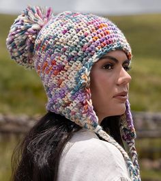 a woman wearing a multicolored crocheted hat with pom - pom