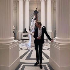 a man in a suit and tie is walking through a room with statues on the walls