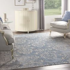 a living room filled with furniture and a rug on top of a hard wood floor