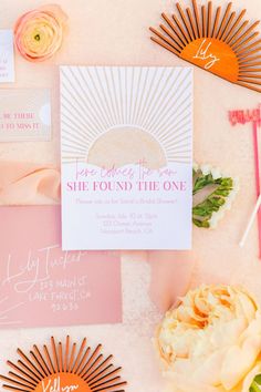 the wedding stationery is laid out with flowers and sunbursts