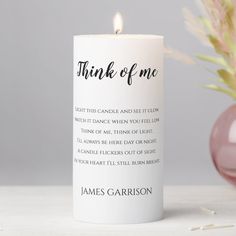 a white candle with the words think of me on it next to a pink vase