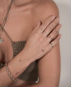 a woman with tattoos on her arm and hand holding onto the wrist, wearing a bra