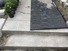 concrete steps with black tarp on them and potted plants