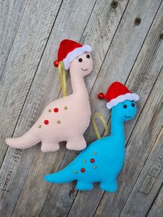 two stuffed dinosaurs wearing christmas hats on top of a wooden fence