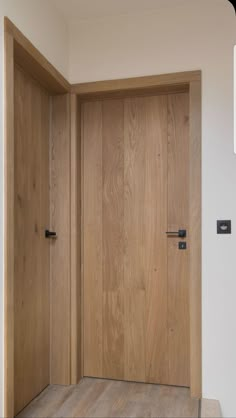 an empty room with wooden doors and wood flooring on the walls, in front of a white wall