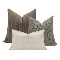 three pillows with different patterns on them, one in grey and the other in brown