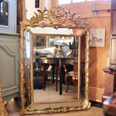 a large mirror sitting on top of a wooden floor next to a chair and table