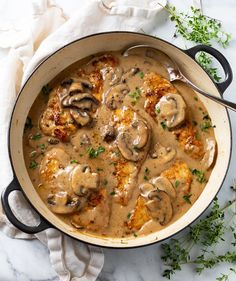 a pan filled with meat and mushrooms covered in gravy on top of a table