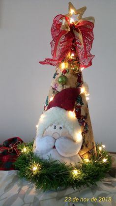 a small christmas tree decorated with lights and a stuffed animal in the middle, sitting on a table