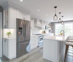 a large kitchen with white cabinets and stainless steel appliances, along with wooden stools